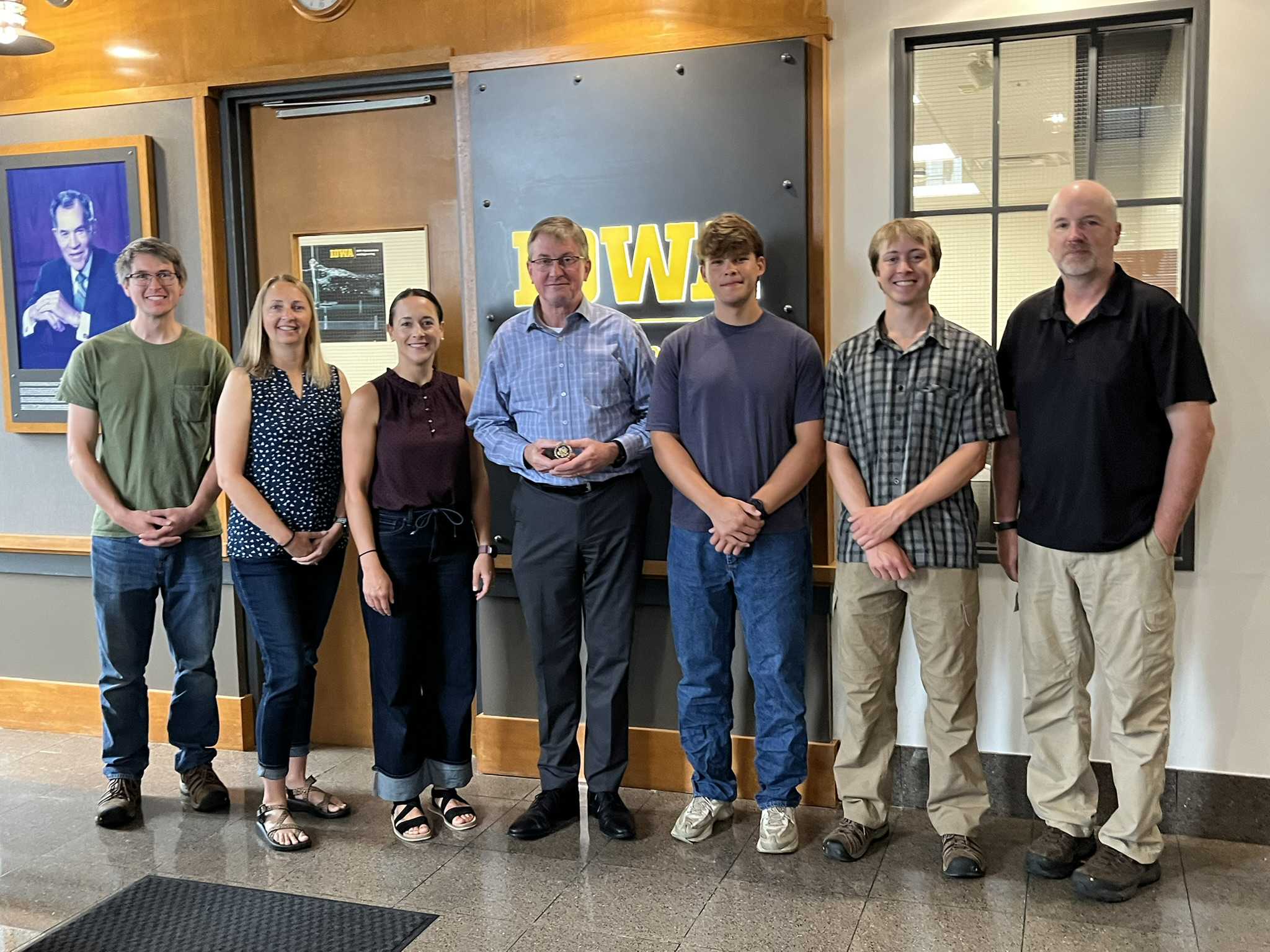 A small group of people poses for a photo in the lobby of the Stanley Hydraulics Lab.