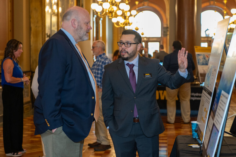 IFC staff discusses his research with a legislator at the Legislative Breakfast event at the Iowa State Capital Rotunda