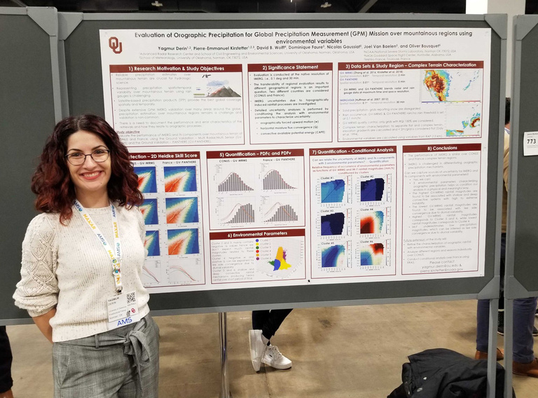 A smiling dark-haired woman poses with a scientific poster documenting her work