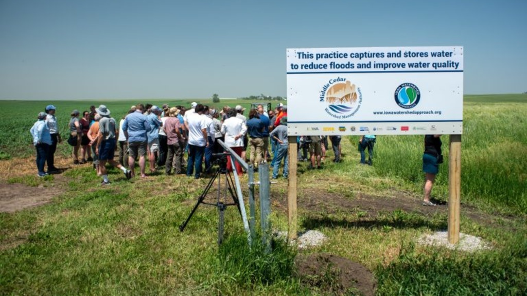 A group of people standing behind a sign identifying a constructed wetland