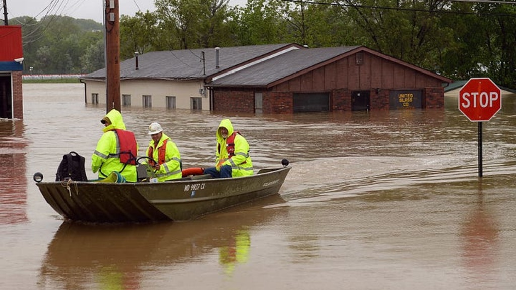 People in rain gear boat through floodwaters