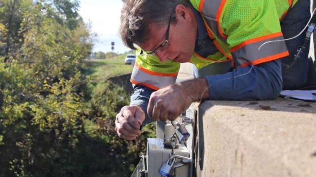 A project engineer installing a flood sensor in a creek