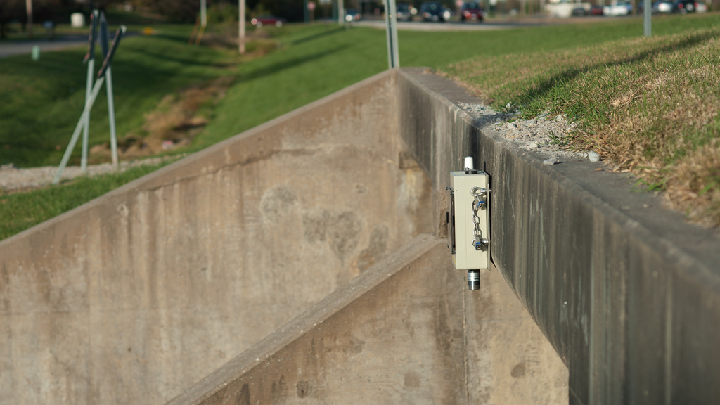A bridge sensor is pictured from the side on a bridge in Iowa City, with the highway in the background